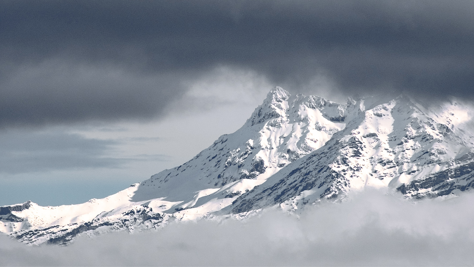 Snow covered mountain amongst clouds.